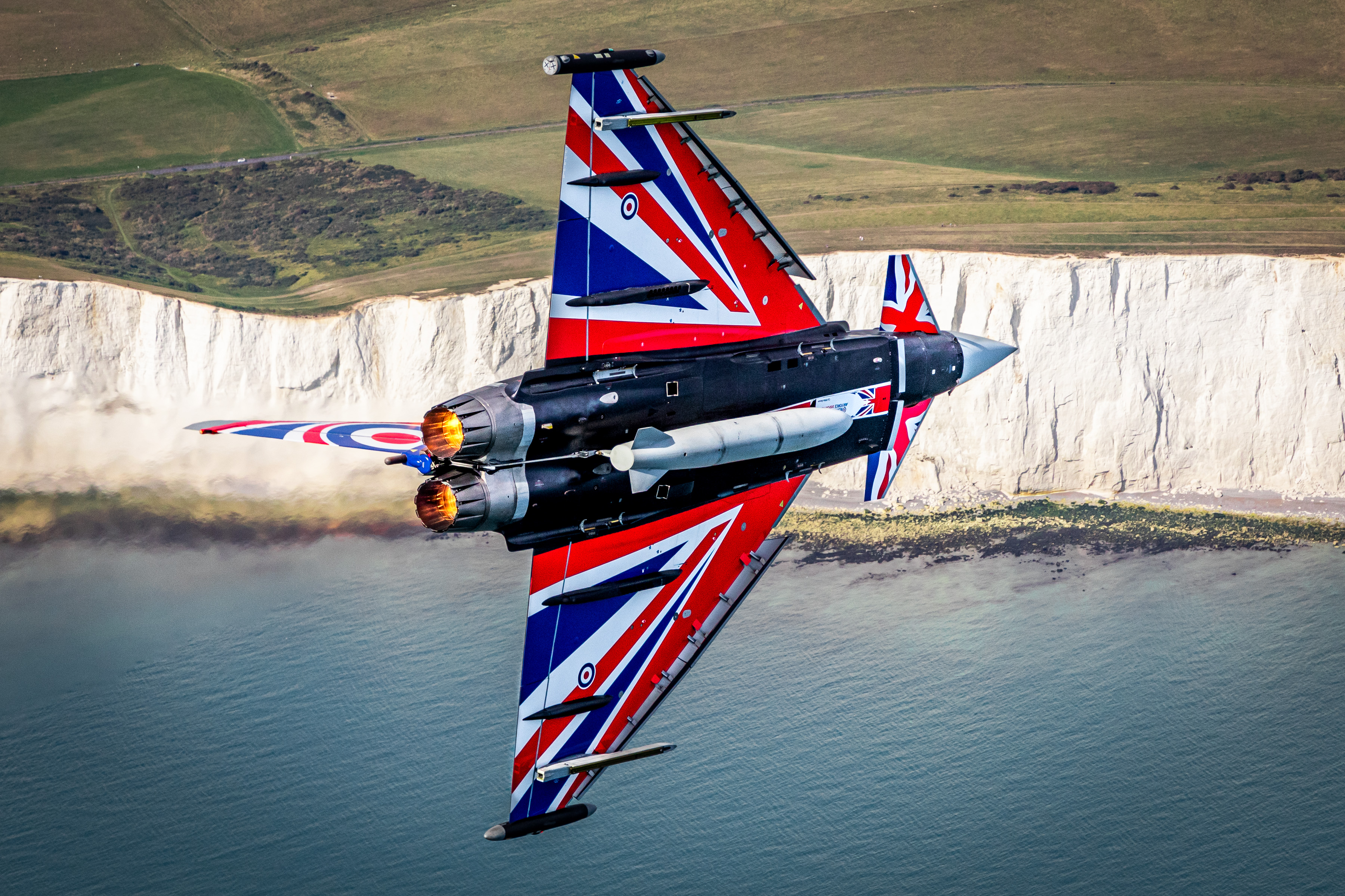 Typhoon with Union Jack painting flies over the sea and white cliffs of Dover.
